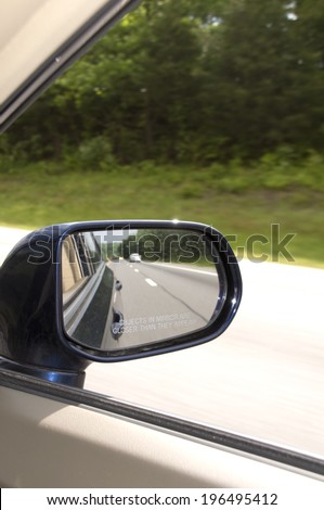 A car mirror reflecting the road behind it.