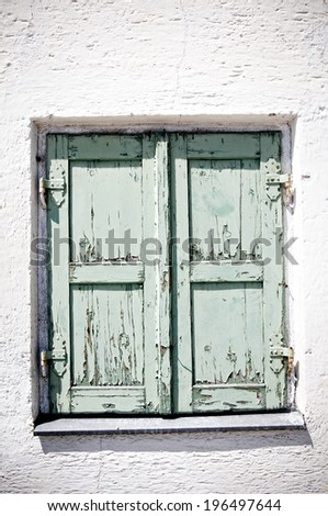 A pair of mint-green closed doors with chipped paint and weathered panels.