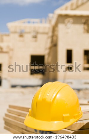 A yellow hard hat sitting on a stack of cut lumber.