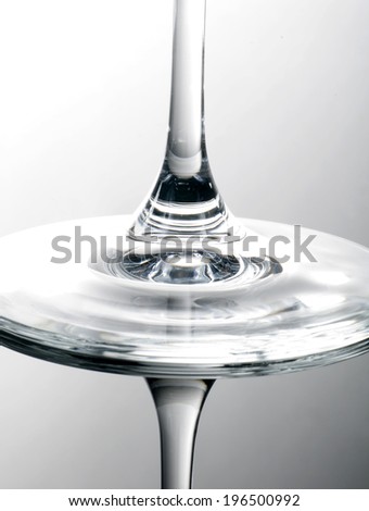 Two wine glasses balanced bottom to bottom with a white background.
