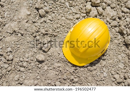 A yellow hard hat on a pile of dirt.