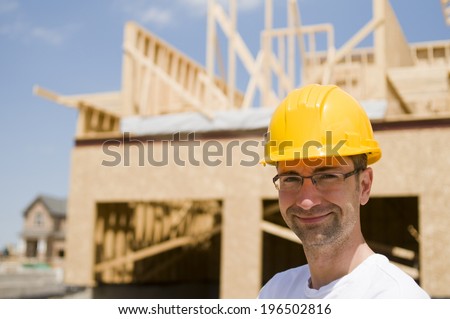 A man wearing a hard hat in front of a construction site.