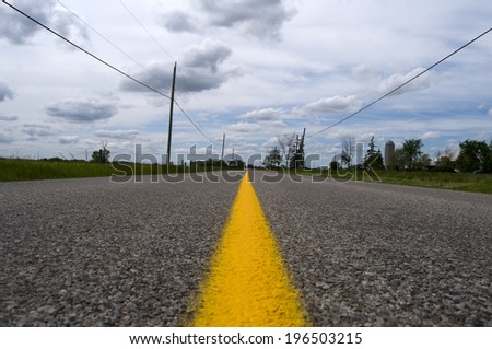 A two lane road with a yellow stripe down the middle.