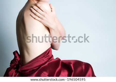 A topless woman with a red satin sheet around her waist.