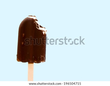 A chocolate covered frozen treat that has a bite taken out of it.