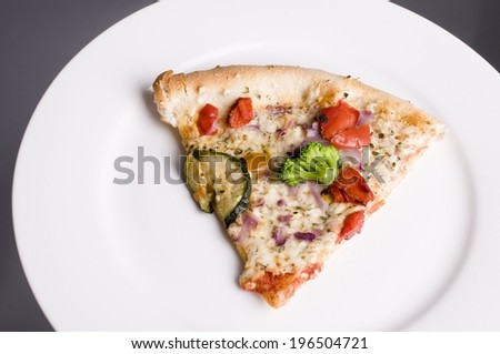 A white plate with a piece of veggie pizza.