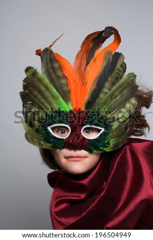 A kid wearing a feathered mask and scarf.