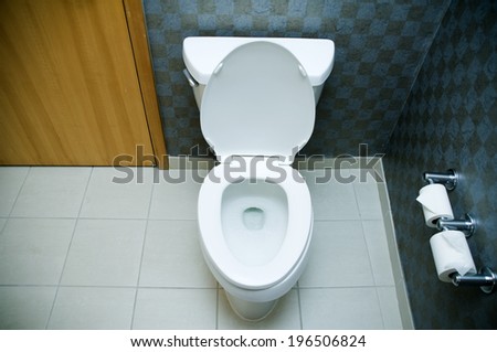 A white toilet in a room with a black wall and white floor.