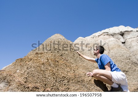 A man approaching the summit of a steep cliff that he has climbed.
