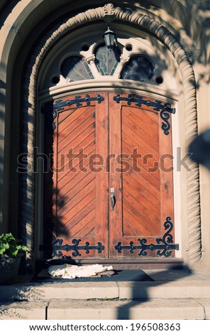 A red double door underneath an ornate arched door frame.