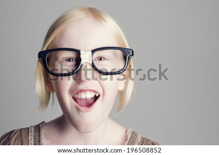 A young blond girl goofing around with oversized nerd glasses.