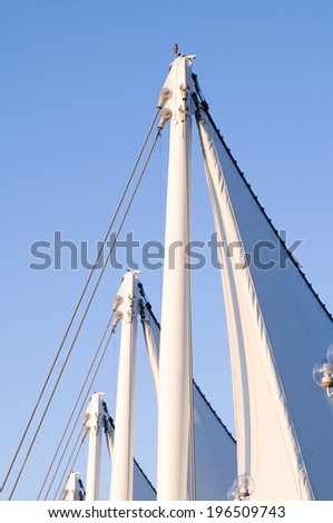 The top of four white masts with sails rigged to the top.
