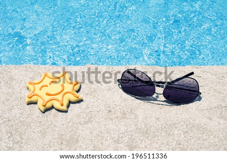 Sunglasses and a sun shaped cookie near the water.