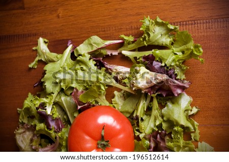 A bright red tomato surrounded by salad leaves.