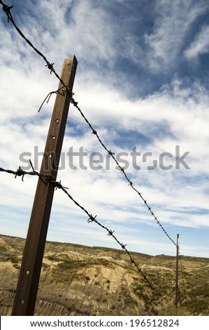 A barbed wire fence and post surrounding a dusty area of land.