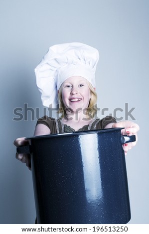 A girl wearing a chef\'s hat and holding a cooking pot.