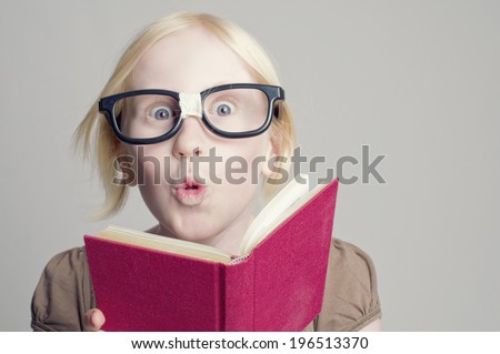 A fair haired girl reading a red book.