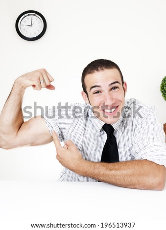 A man in a tie who is smiling while flexing and pointing to his arm muscles.