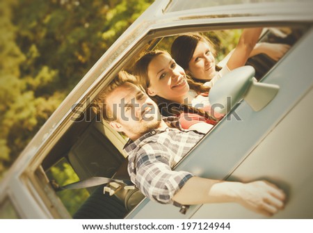 A man and two women in the front seat of a car.