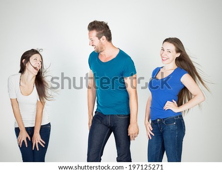 Two women and a man standing and laughing.
