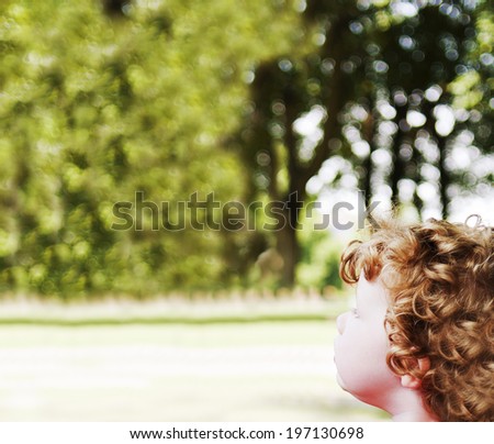 A young child with very curly hair looks onward.