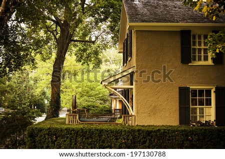 A yellow house with a patio surrounded by hedges.