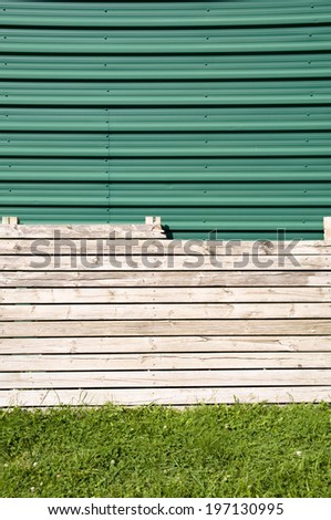 A wood fence sits in front of a green, metal garage door.