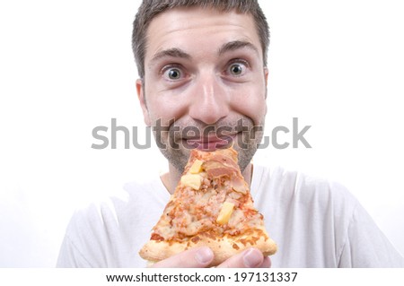 A man with a closed mouth grin and wide eyes holding a slice of pizza.