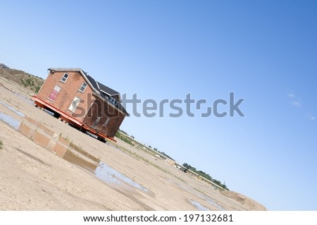 An isolated house on a sandy ground with some wet areas.