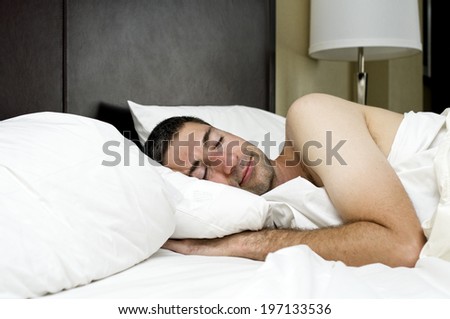 A man sleeping in a bed with white sheets.