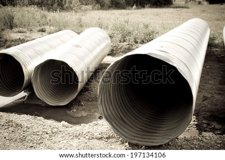 Metal water pipes laying on the gravel outdoors.