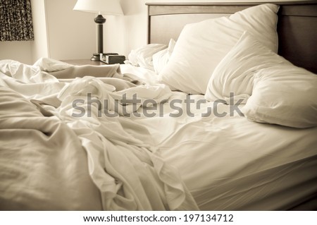 An unmade bed with pillows, sheets, and a blanket.