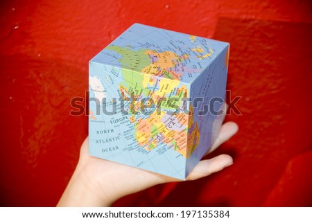 A person holding a cube-shaped globe in their hand.