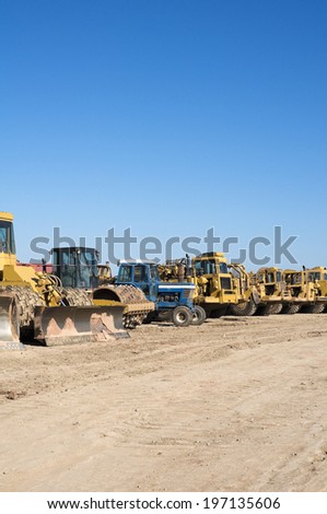 A variety of heavy duty machinery lined up together in a yard.