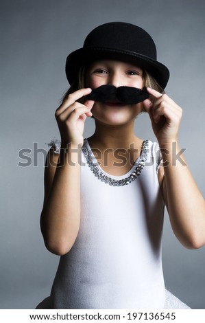 A child in a bowler hat holding a fake mustache to her face.