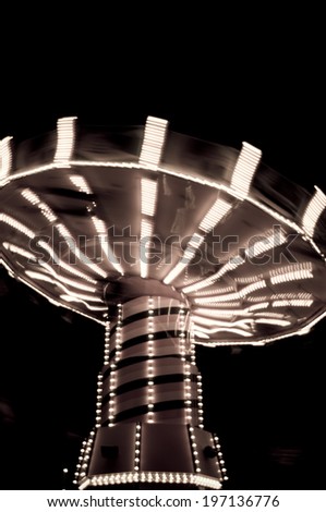 A carnival ride with light spinning around at night.