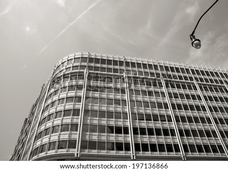 A multi window building stands against a cloudy sky.