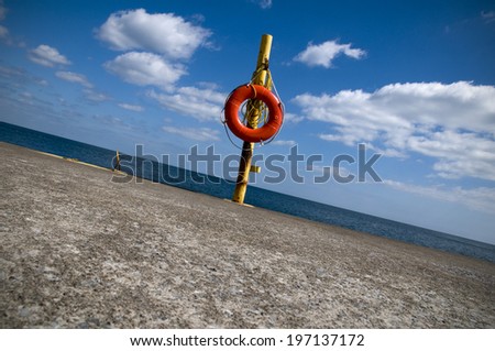 A life preserver on a pole at the beach.