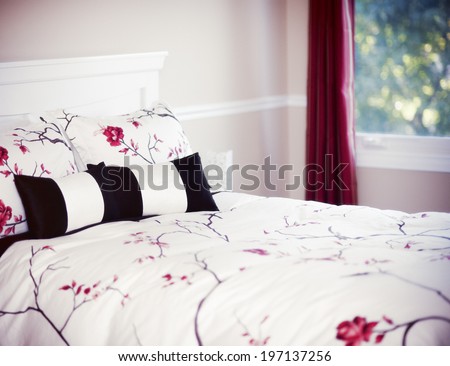 Bedroom with Queen sized bed, white comforter with roses, and red drapes.