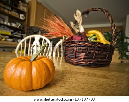 A wicker hamper basket and a pumpkin situated on a table.