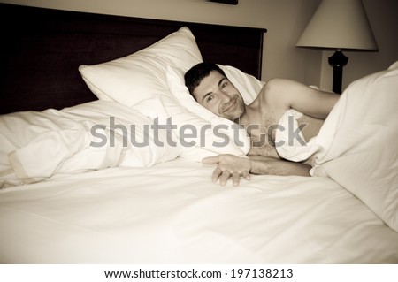 A man in bed with pillows and sheets.