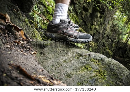 A man in tennis shoes standing on a rock.