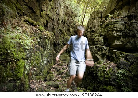 A man walking through a rocky path between two cliffs.