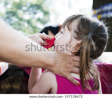 A mother wiping the face of a female child.