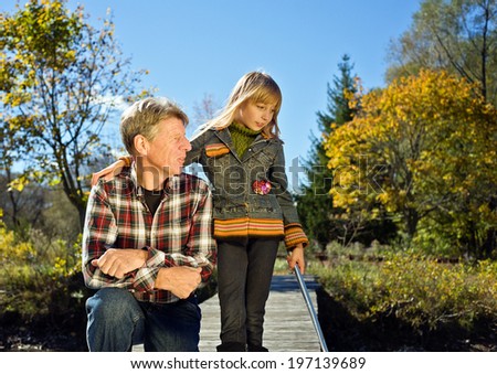 A girl standing beside a man outside on a sunny day.