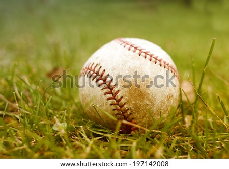 An old baseball lying on a field during the day.
