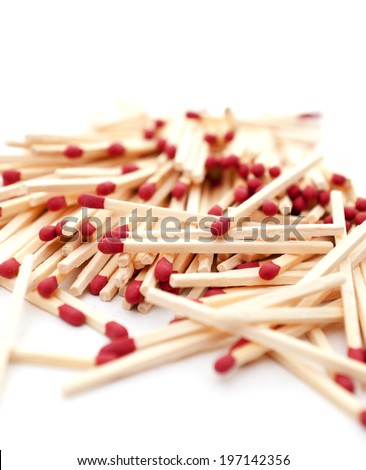 A pile of red-tipped matchsticks scattered haphazardly on a flat surface.