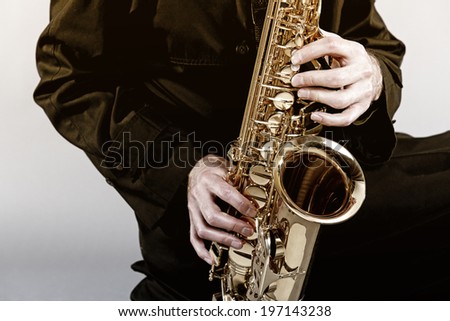 An instrument of polished brass being played by a dark cloaked stranger.