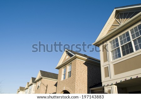 Six corners of sandstone colored houses set against a blue sky.