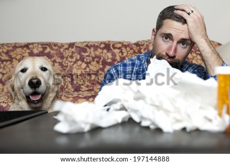 A man and a dog sit on a couch where a tablet bottle can be seen.